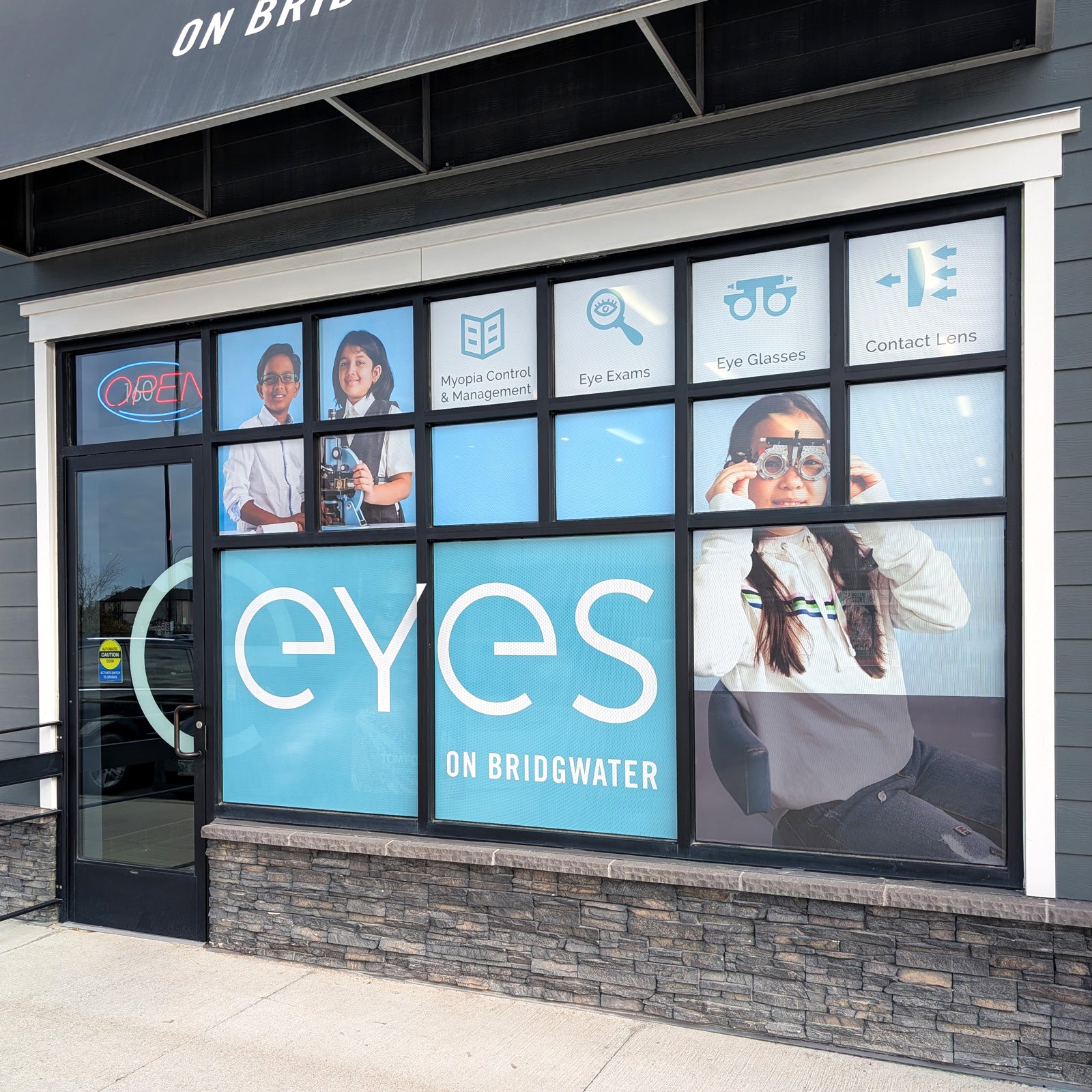 Storefront with 'eyes on Bridgwater' branding and images of people wearing glasses.
custom door decals, entrance door decal, door decals Winnipeg, custom window decals graphics stickers, perforated window decals graphics stickers, removable window decals graphics, permanent window decals graphics stickers, frosted window decals graphics, vinyl lettering, window decals graphics stickers Winnipeg, window decals graphics stickers Manitoba, window decals graphics stickers fast